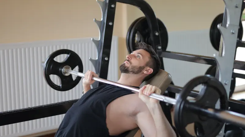 Un homme soulève une barre au développé couché dans une salle de sport.